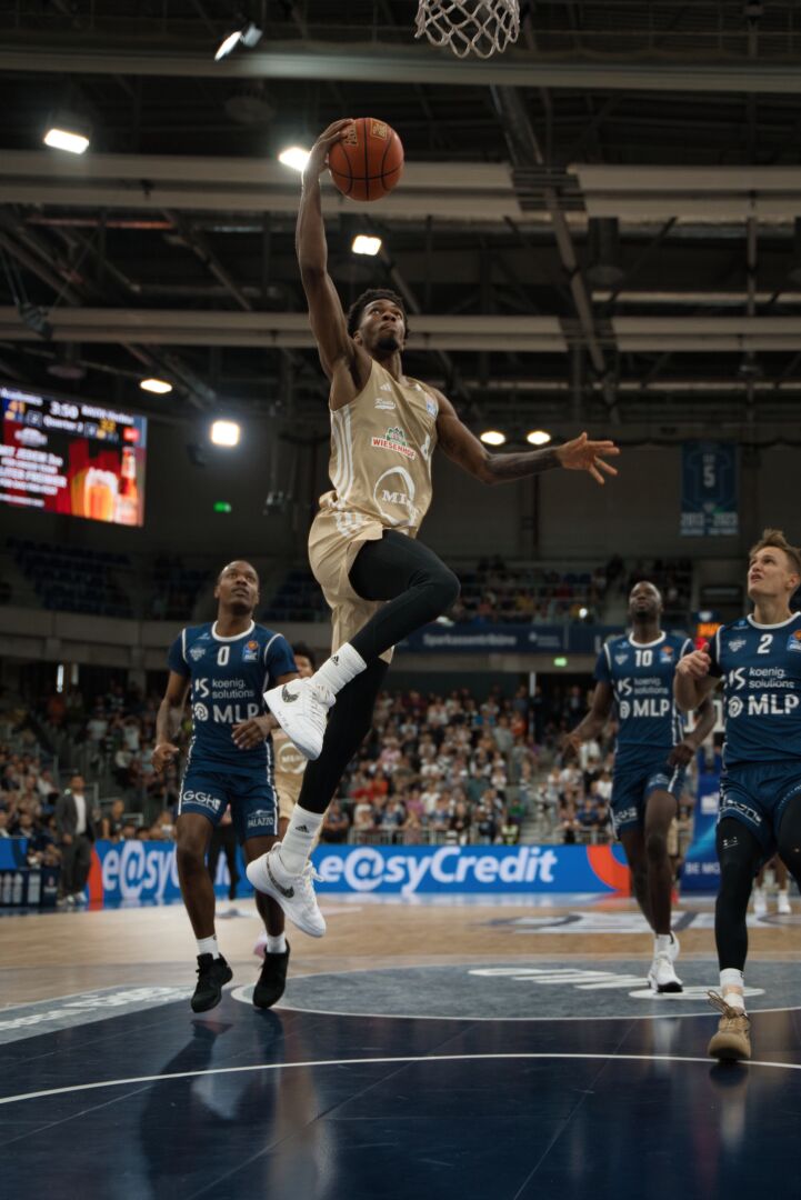 Basketball-Dunking-Action – Ein Spieler springt zum Korb, festgehalten von einem professionellen Fotografen und Filmemacher für Sportevents.