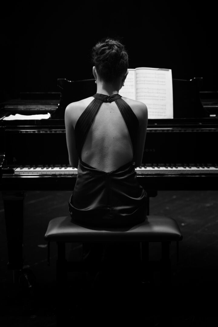 Klavierspielerin in der Rückansicht – Künstlerisches Bild einer Musikerin in schwarz-weiß.